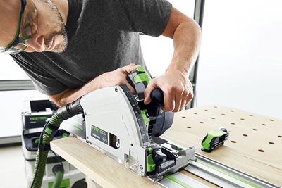 Bărbatul taie cu ferăstrăul circular Festool o scândură pe o masă multifuncţională