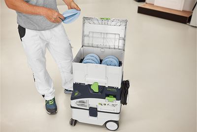 Un meşter se află lângă un Systainer plin de material abraziv