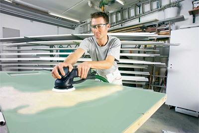 O persoană şlefuieşte o suprafaţă vopsită în verde