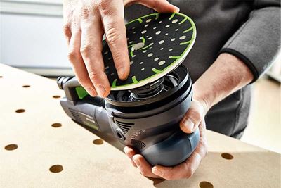 Un meşter aşază talpa de şlefuire pe un şlefuitor Festool