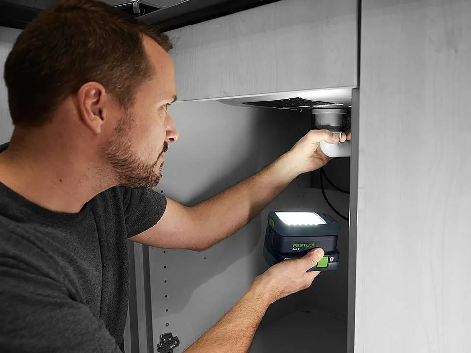 Un bărbat iluminează conexiunea unei chiuvete cu SYSLITE KAL 2