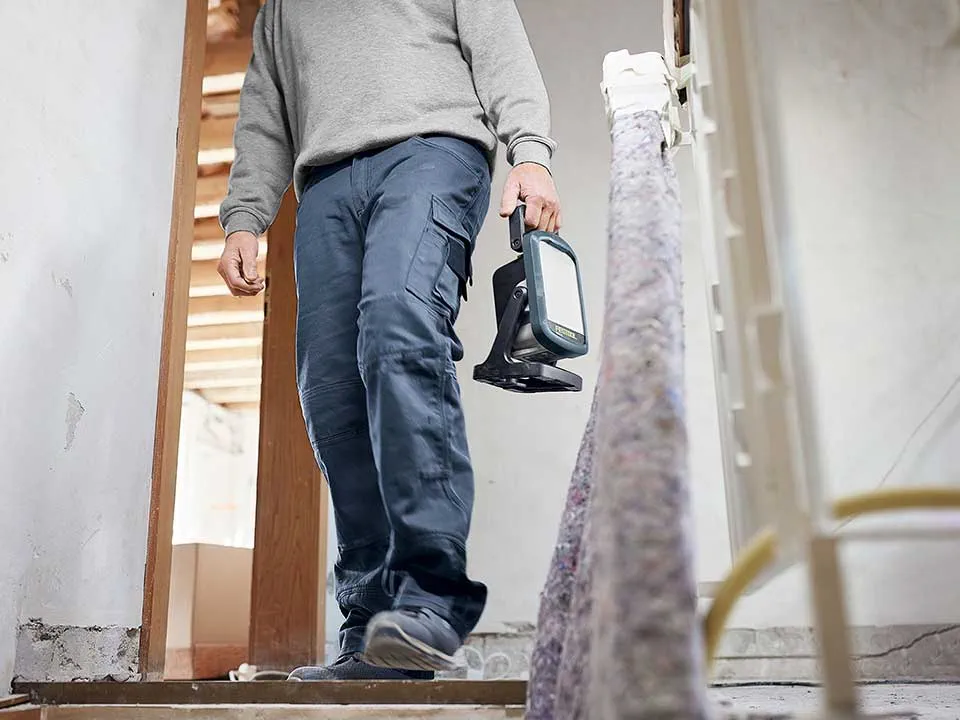 Un meșter poartă un proiector pentru construcții