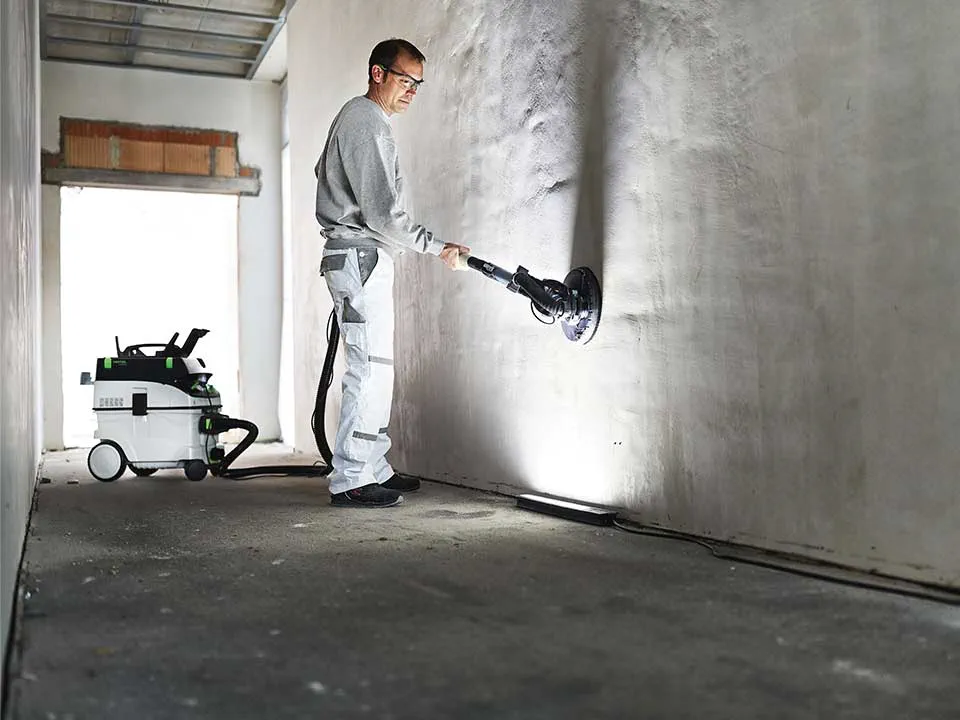 Un meșter iluminează un perete cu ajutorul Evidențierii pictorului și îl șlefuiește